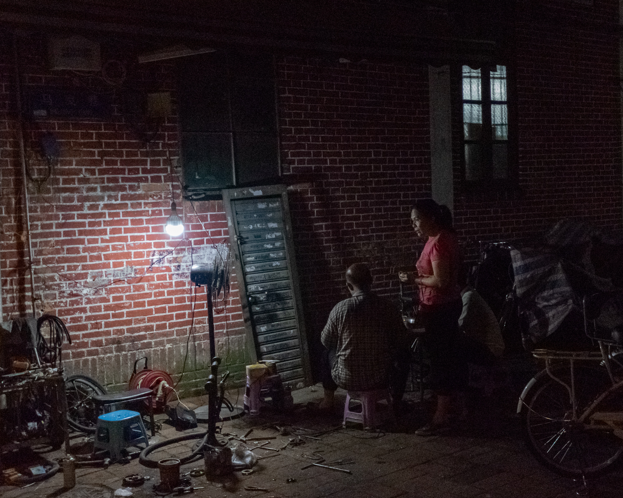 Late night bicycle repair under a bare bulb, Guangzhou China