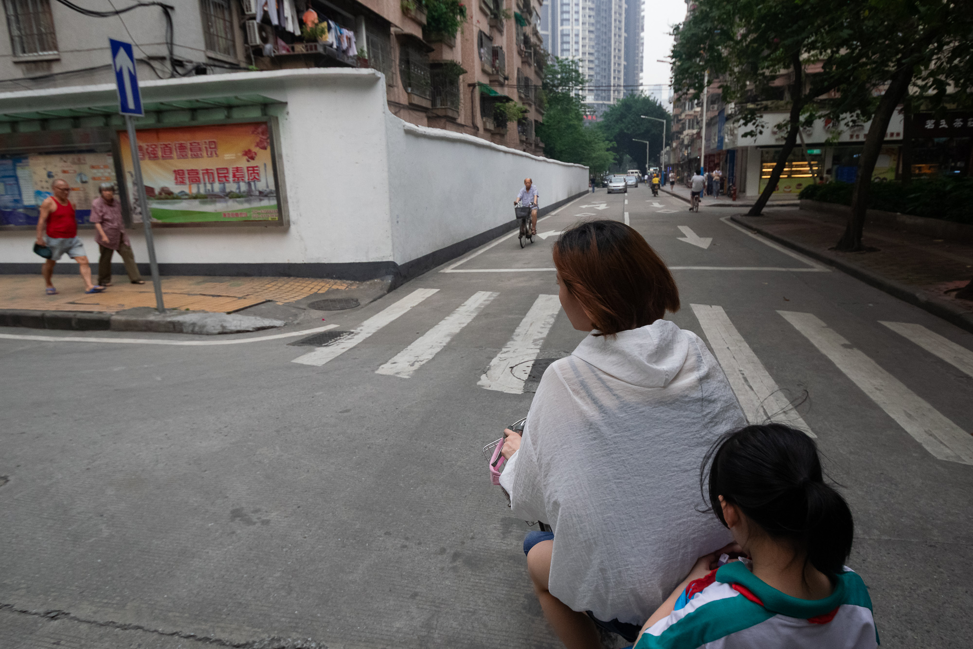 Scooter passenger view of a Guangzhou side street with cyclist and pedestrians