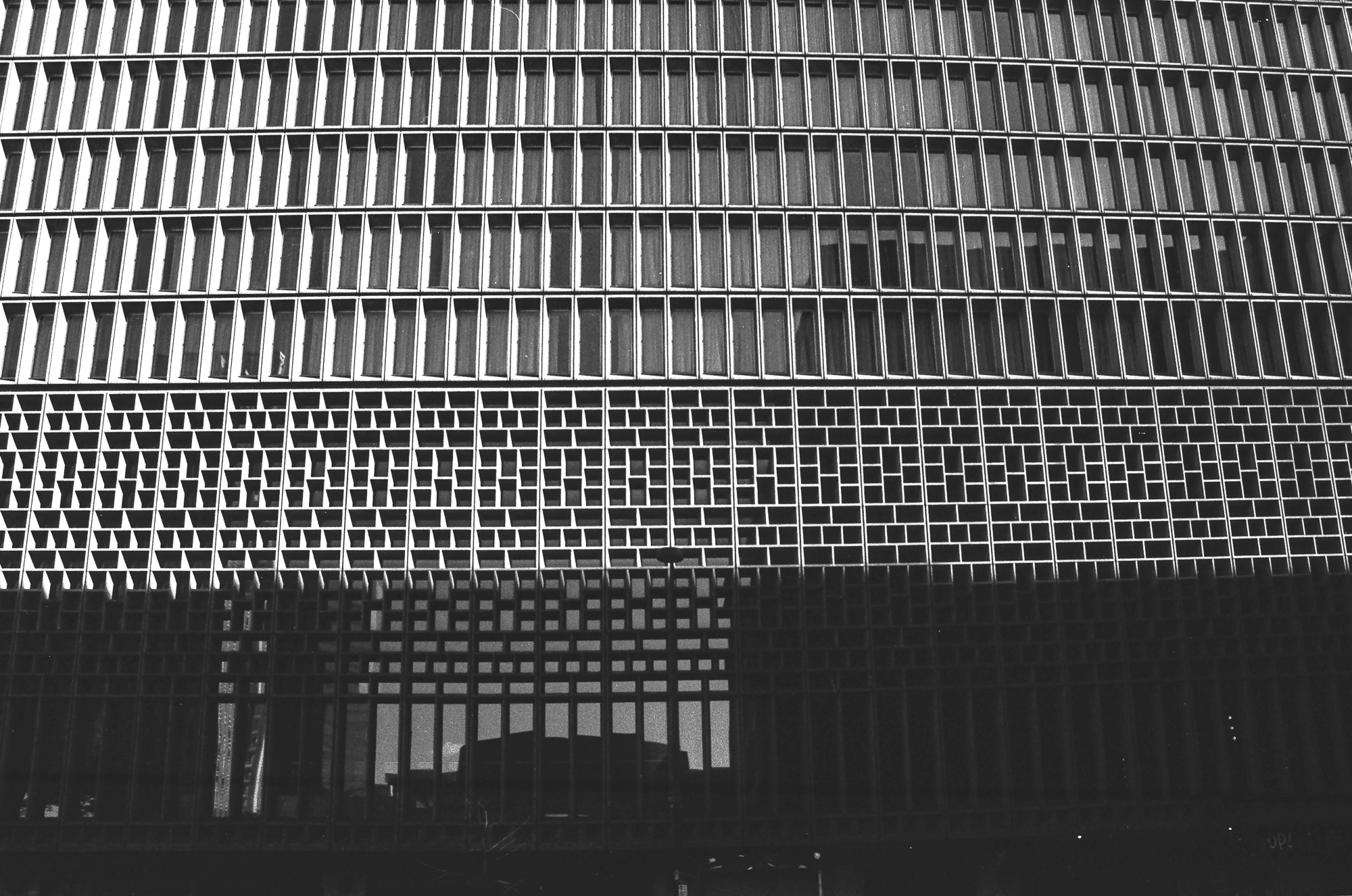 The geometric facade of a Denver brutalist building — two registers of grid patterns, windows and tiles, analog black and white