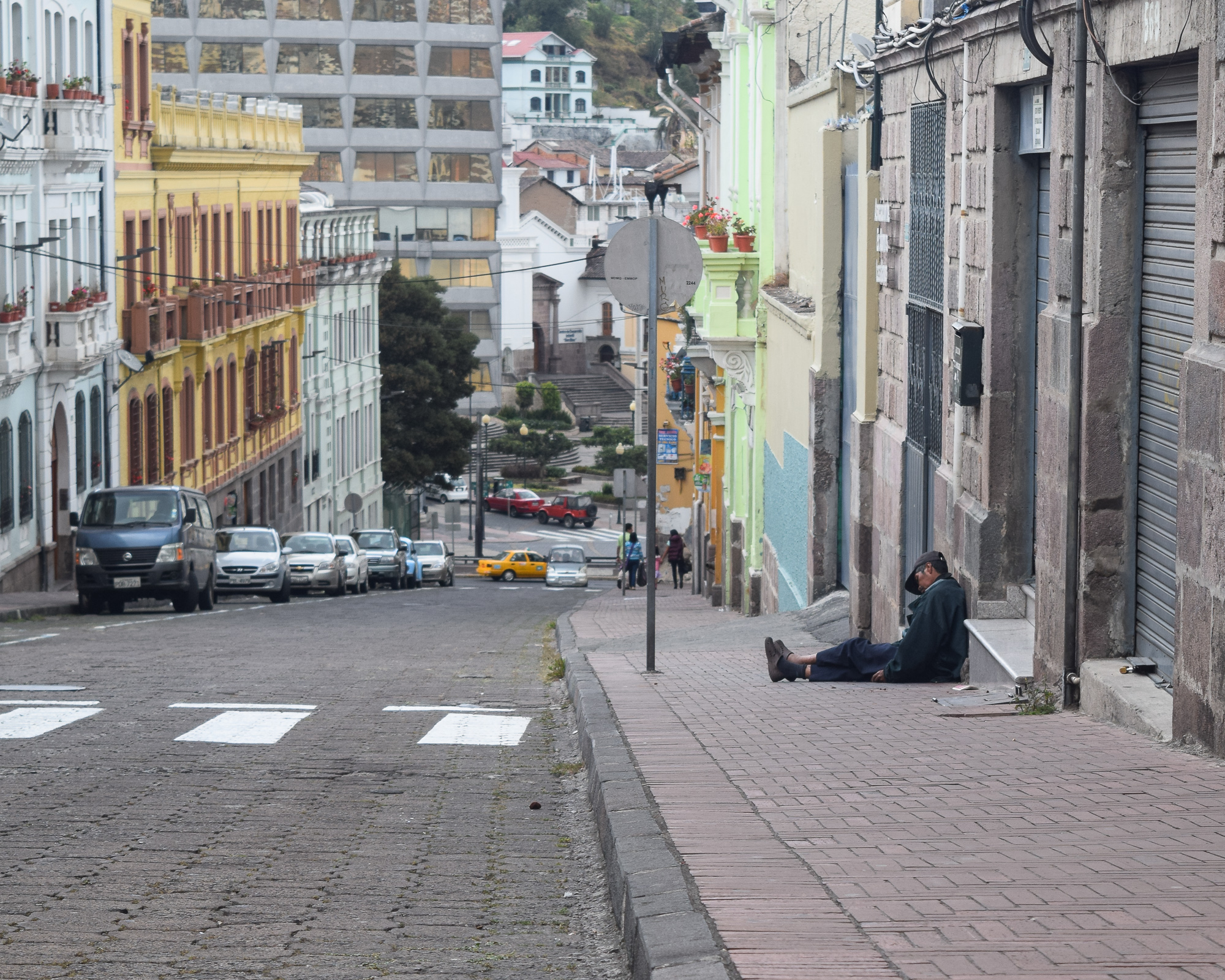 A busy Quito intersection — white colonial facade, a little girl being led through the crowd