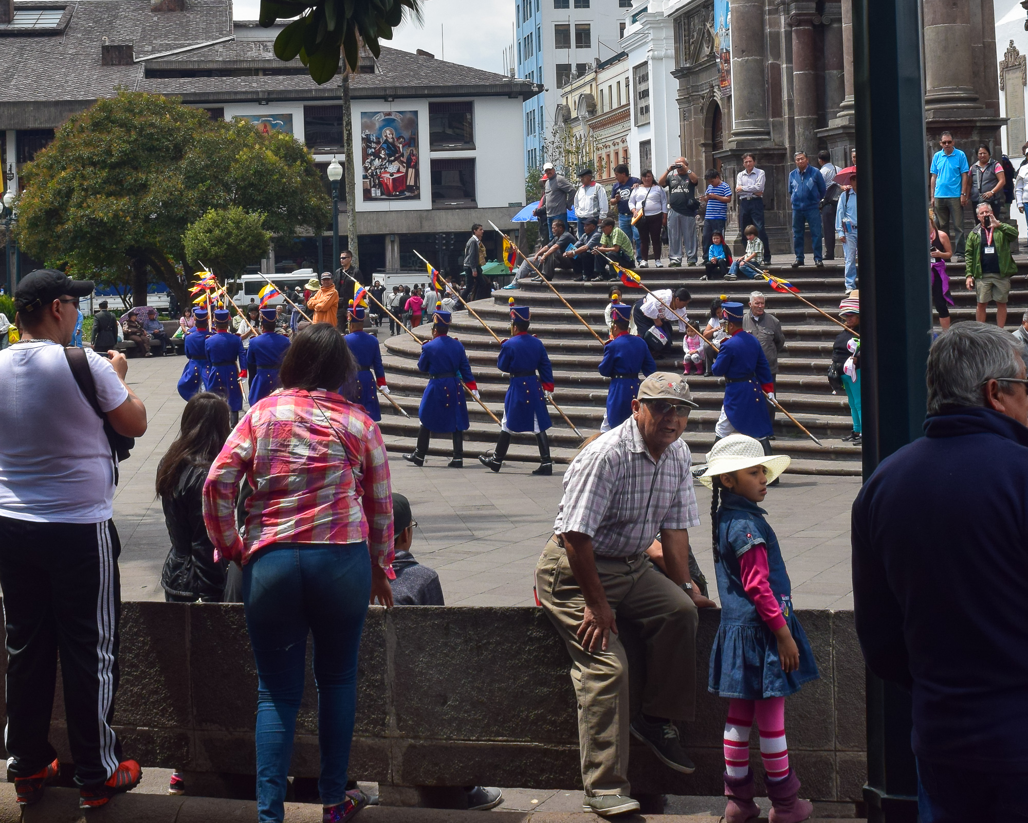 A parade in the Quito plaza — blue-uniformed guards, spectators watching casually