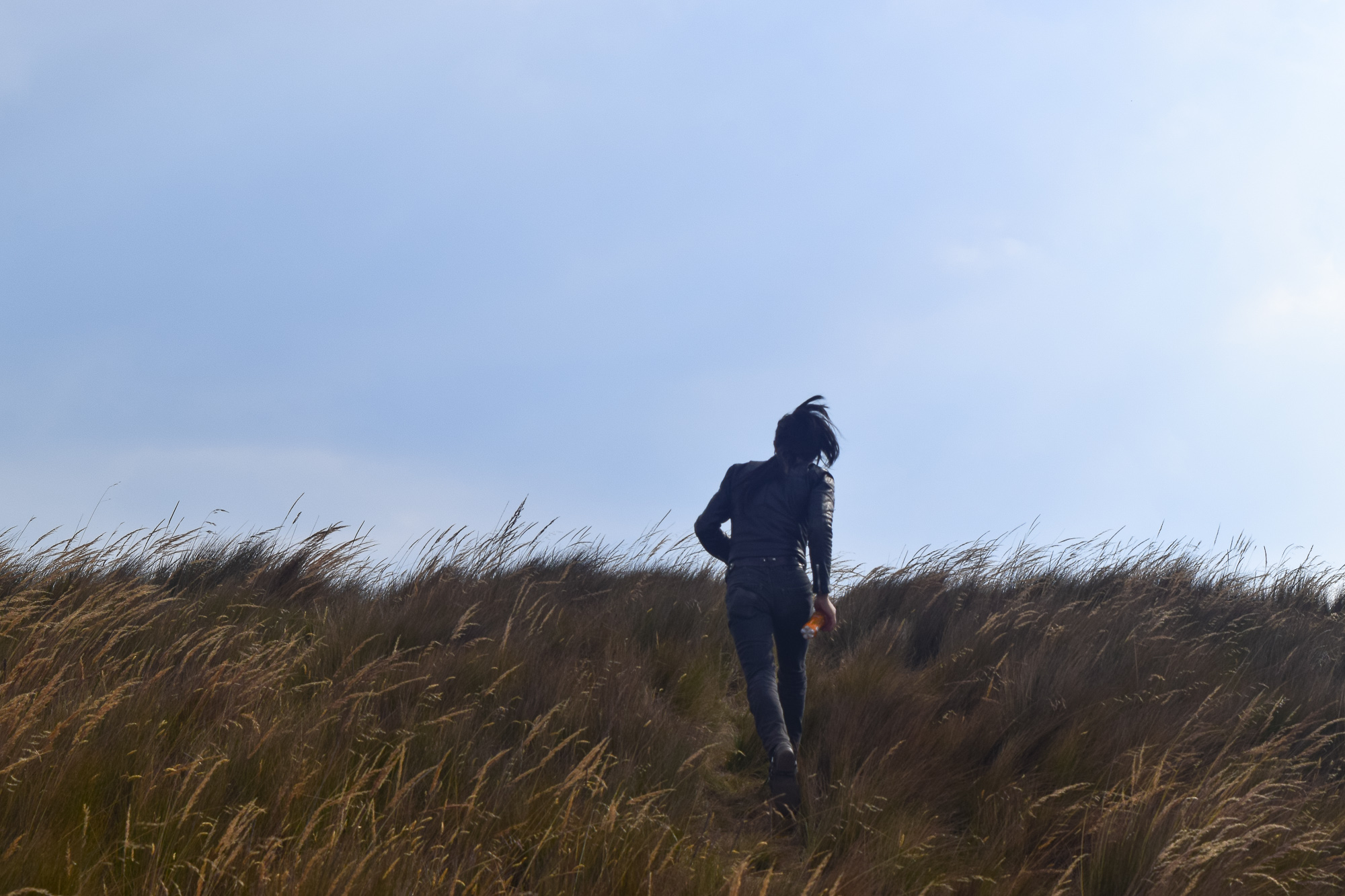 A tight portrait on the Quito páramo — sunglasses and scarf pulled up against the wind, mountain ridge behind