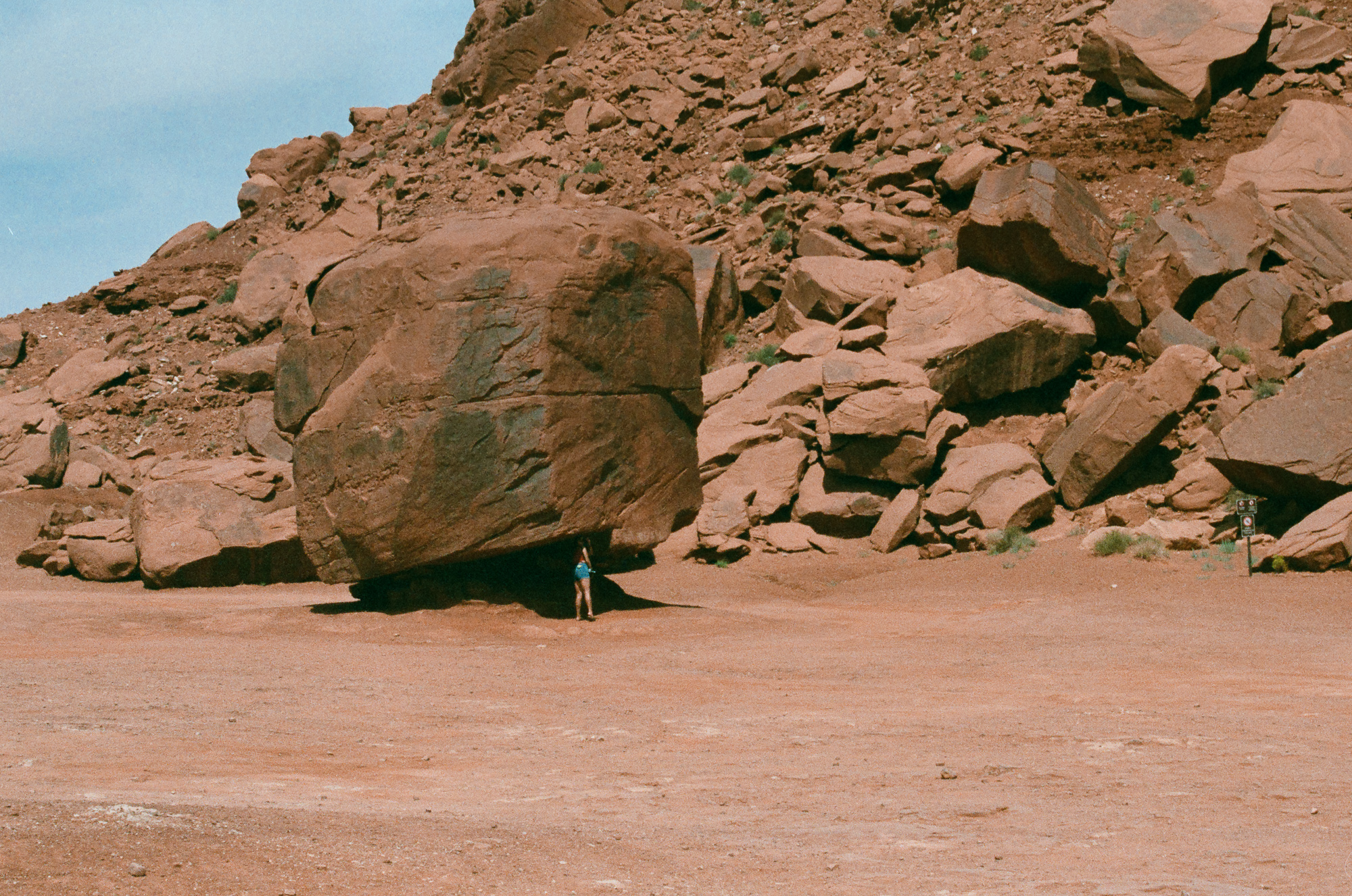 Tiny figure beneath a massive red boulder at Monument Valley, 35mm analog black and white