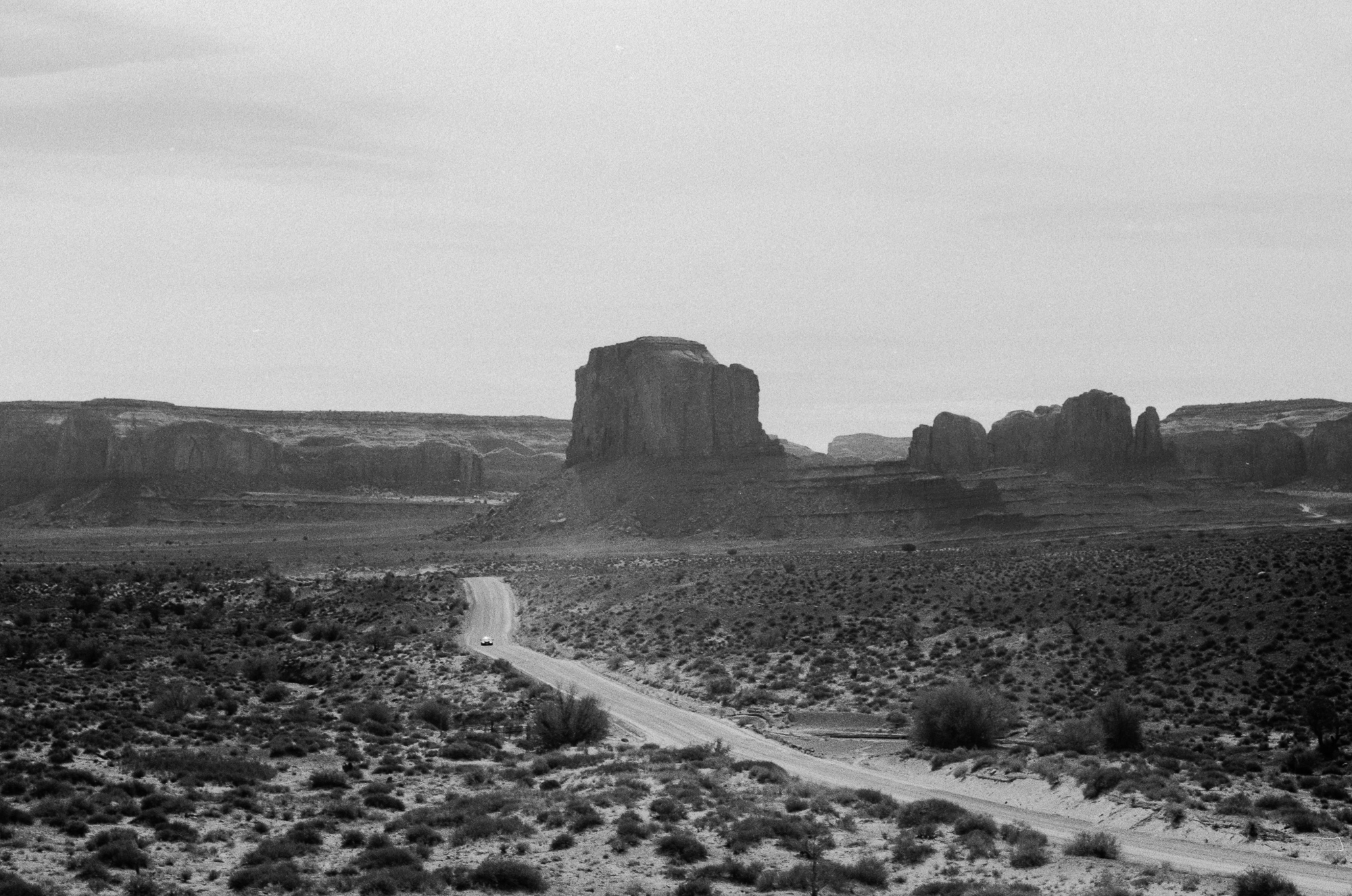 Lone car on the Monument Valley road, 35mm film, analog black and white