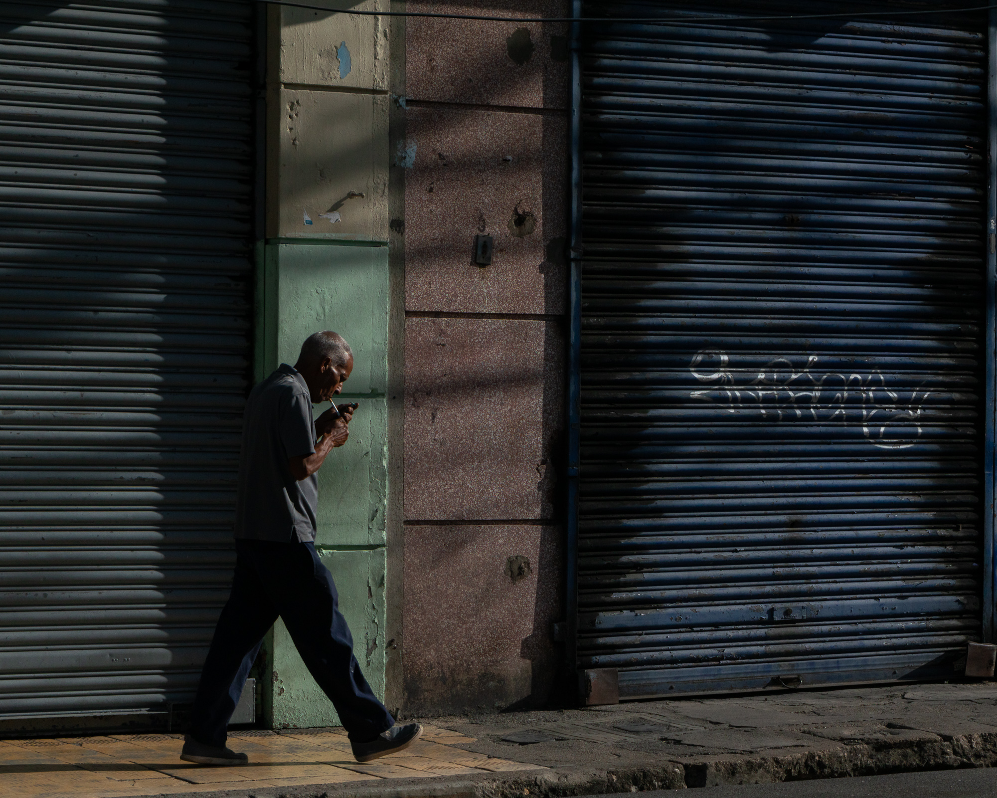 A second figure moving through light and shadow in Santo Domingo — companion to the previous