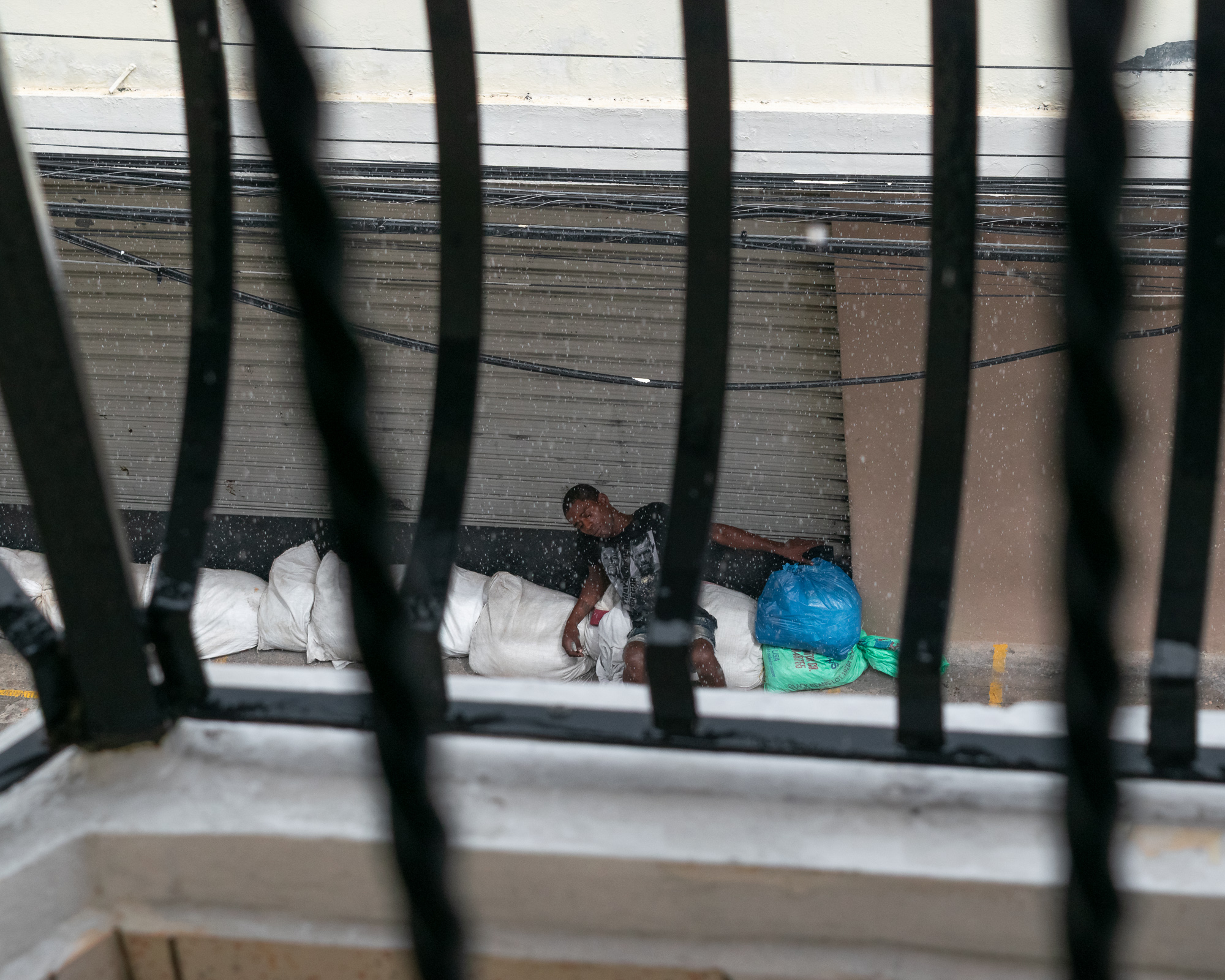 A man asleep in the rain in Santo Domingo — candid portrait, social reality