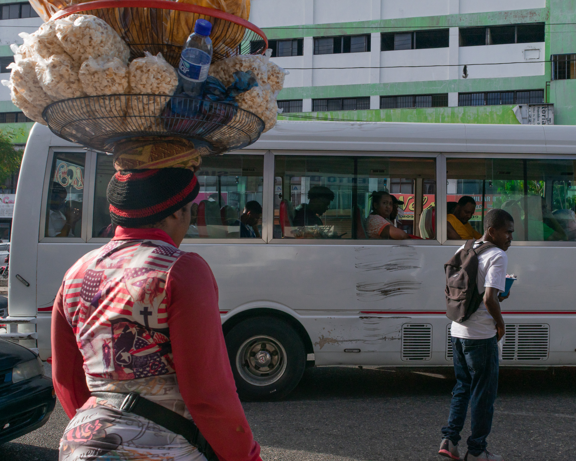 A woman vendor at a Santo Domingo bus stop — purposeful, spontaneous, strong color