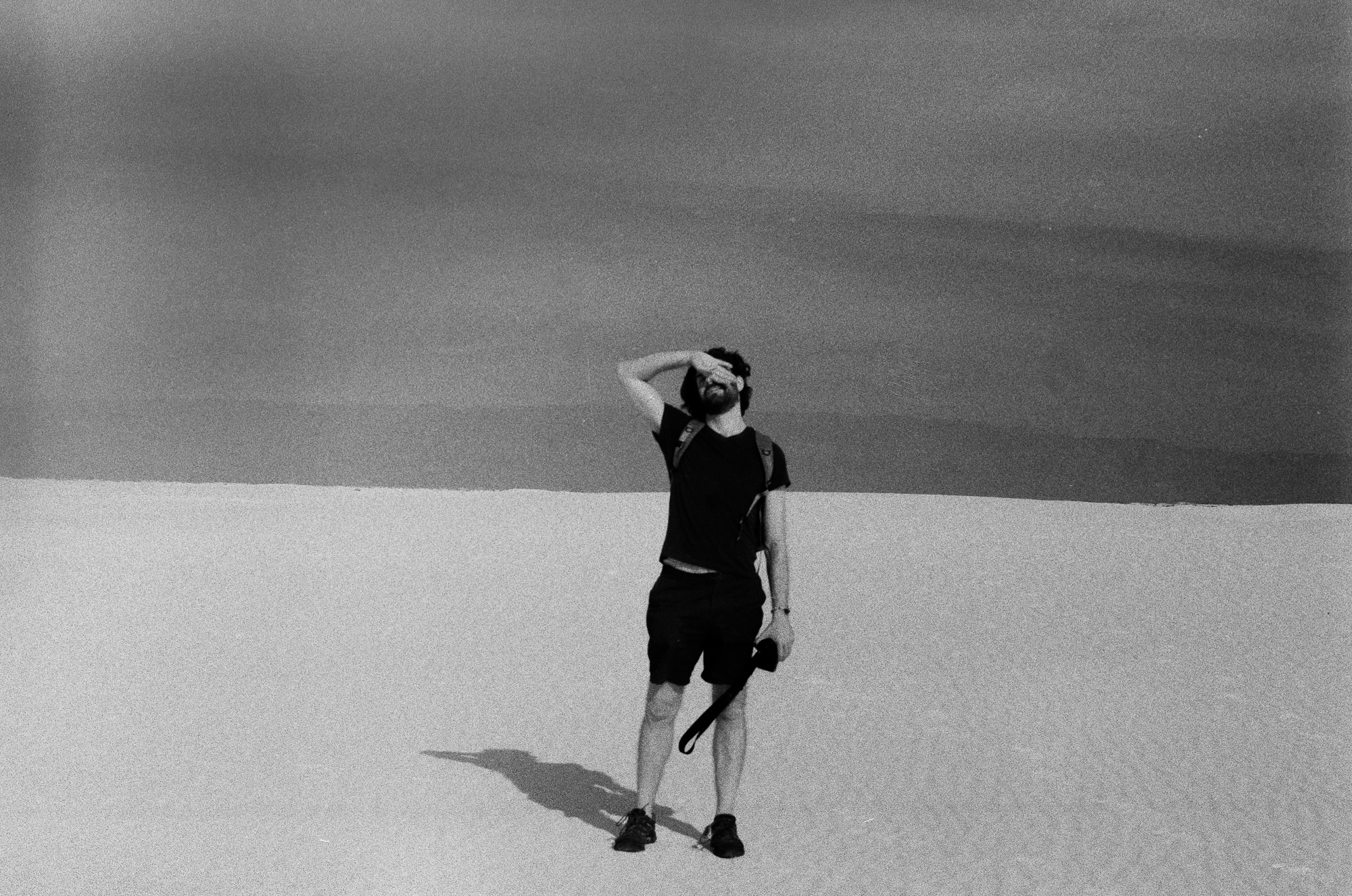 Hiker shielding eyes on White Sands dune, 35mm film